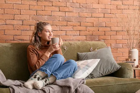 Frau lässt es sich auf Couch mit Kakao gut gehen